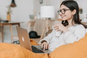 a woman infront of laptop while having a coffee and smiling